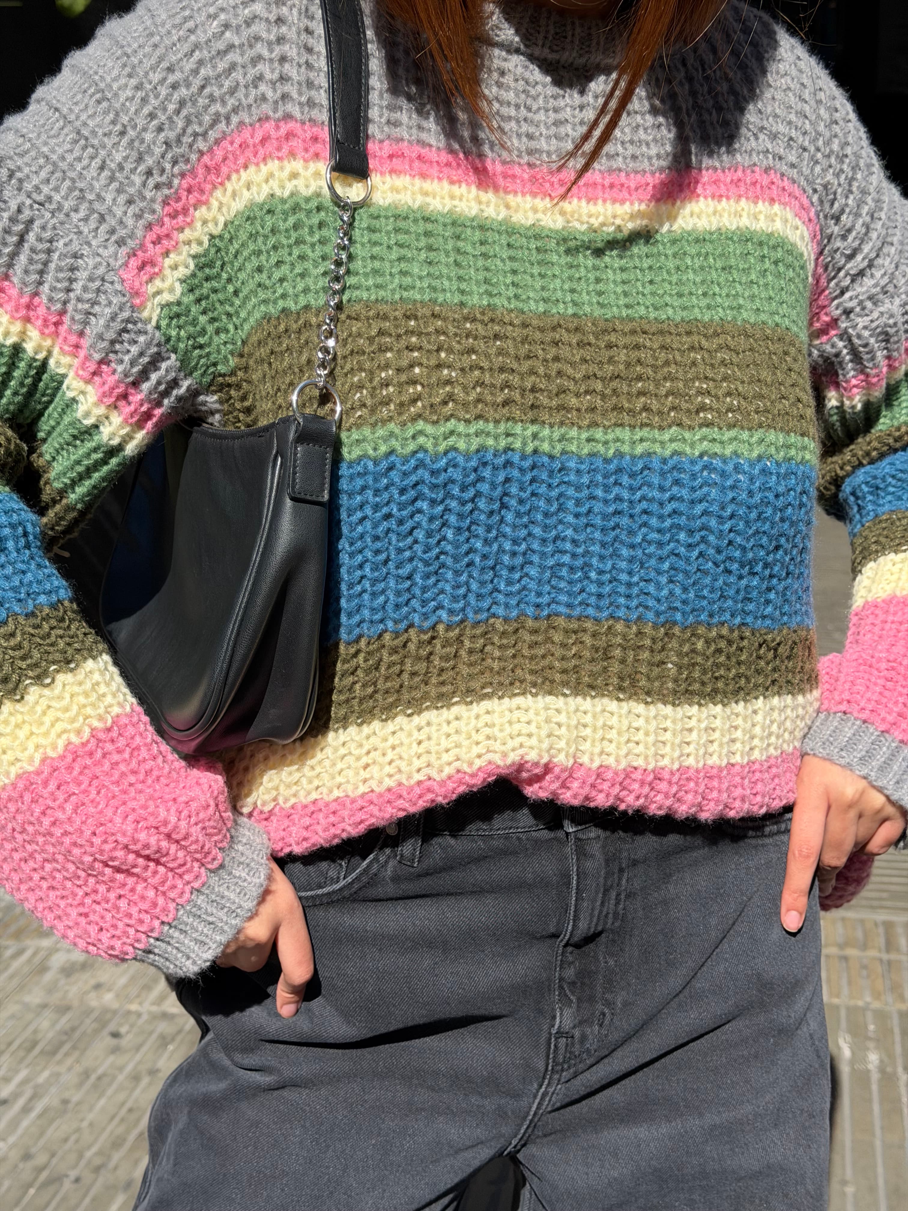 Detalle de sweater tejido de colores y bolso negro
